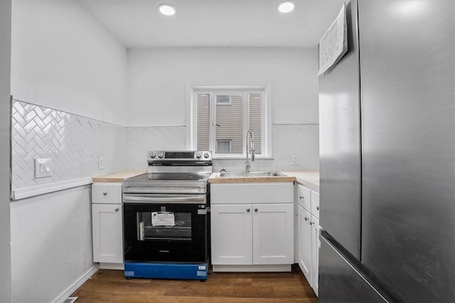 kitchen with stainless steel appliances, sink, dark wood-type flooring, and white cabinets