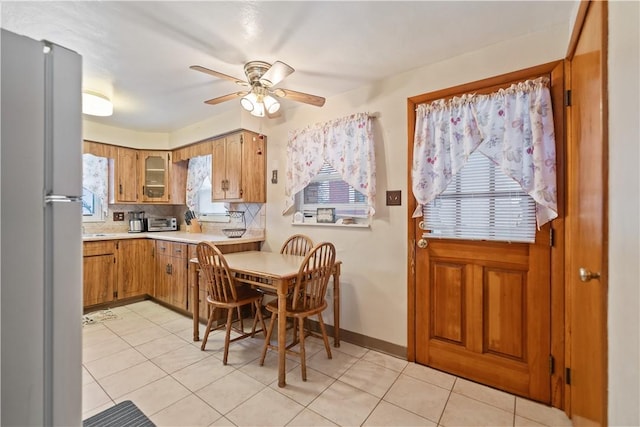 kitchen featuring tasteful backsplash, ceiling fan, light tile patterned flooring, and stainless steel refrigerator