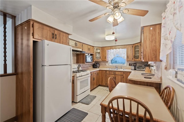 kitchen featuring light tile patterned floors, white appliances, sink, ceiling fan, and backsplash