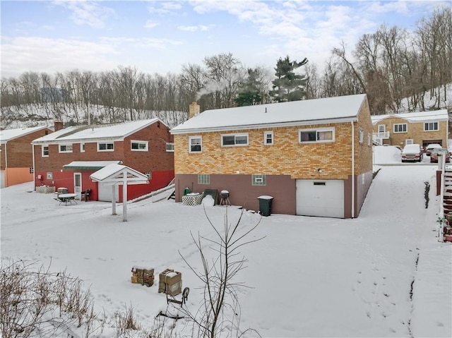 snow covered rear of property featuring a garage