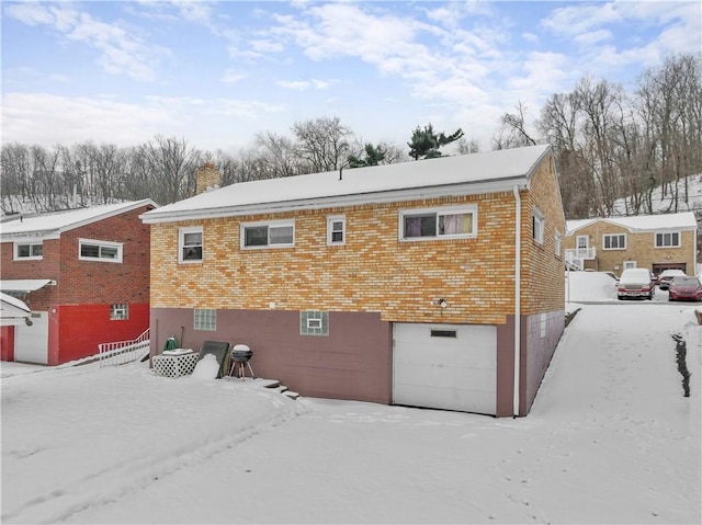 snow covered rear of property featuring a garage