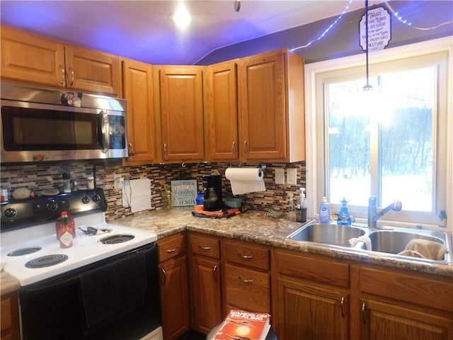 kitchen with stainless steel microwave, brown cabinetry, a sink, and range with electric stovetop