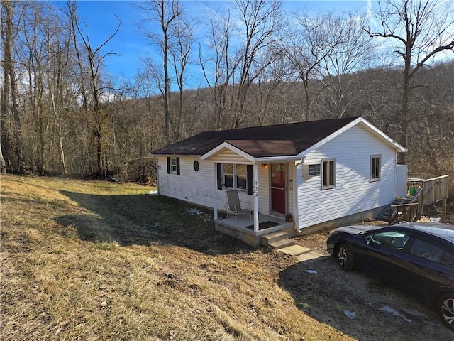 view of front of property with a front yard and a forest view