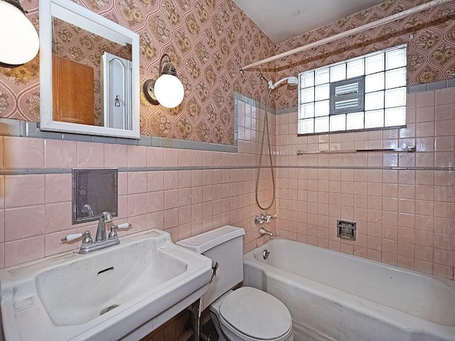 full bathroom with tiled shower / bath, sink, tile walls, and toilet