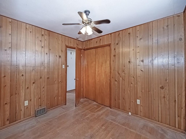 spare room with ceiling fan, wood-type flooring, and wood walls