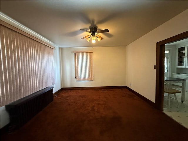 spare room featuring ceiling fan and dark colored carpet