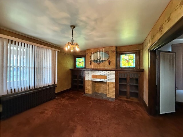 unfurnished living room featuring dark carpet, an inviting chandelier, and a fireplace