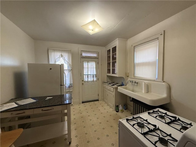 kitchen featuring white cabinetry, white appliances, and dark stone countertops