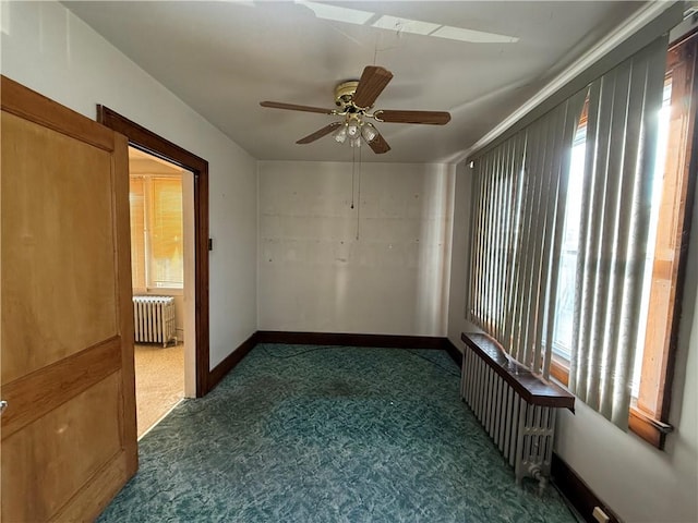 empty room featuring ceiling fan, radiator heating unit, and dark carpet