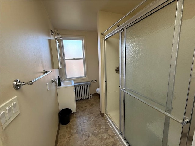 bathroom featuring a shower with door, radiator heating unit, and toilet