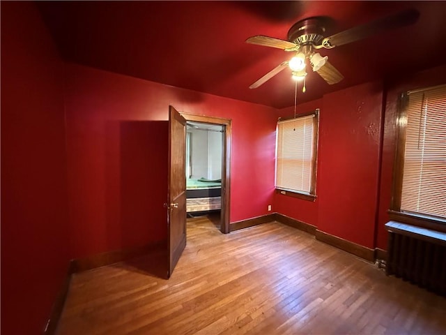 unfurnished bedroom featuring hardwood / wood-style flooring, radiator heating unit, and ceiling fan