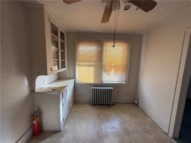 unfurnished dining area with radiator, built in shelves, and ceiling fan