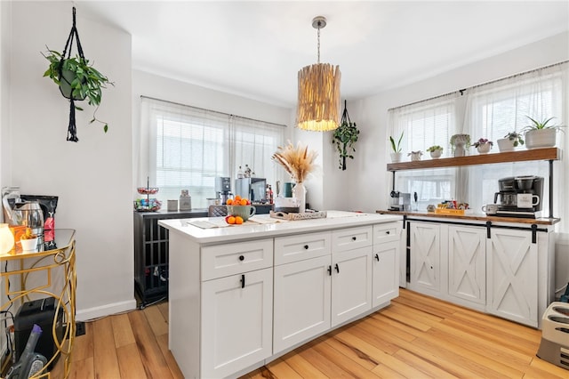 kitchen featuring light wood-type flooring, hanging light fixtures, and white cabinets