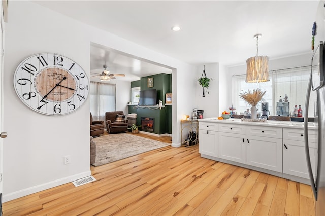 kitchen featuring pendant lighting, white cabinets, fridge, ceiling fan, and light hardwood / wood-style flooring