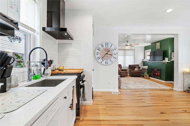 kitchen with white cabinets, a wealth of natural light, white dishwasher, and wall chimney range hood