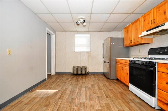 kitchen with gas stove, a paneled ceiling, light wood-type flooring, stainless steel fridge, and radiator