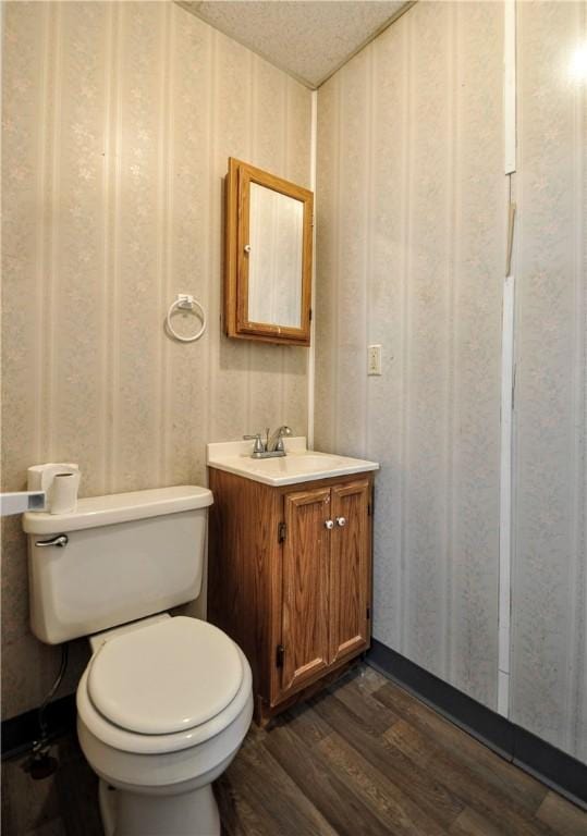 bathroom with hardwood / wood-style flooring, vanity, toilet, and a textured ceiling