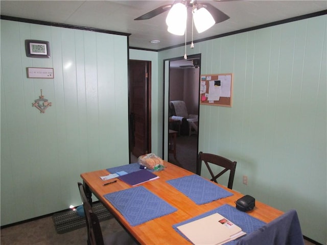 dining area with ornamental molding, ceiling fan, and wood walls