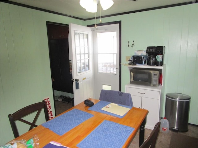 dining space featuring ornamental molding and wood walls