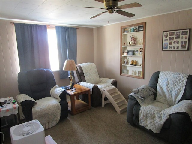 living area with built in shelves, wooden walls, ceiling fan, and carpet