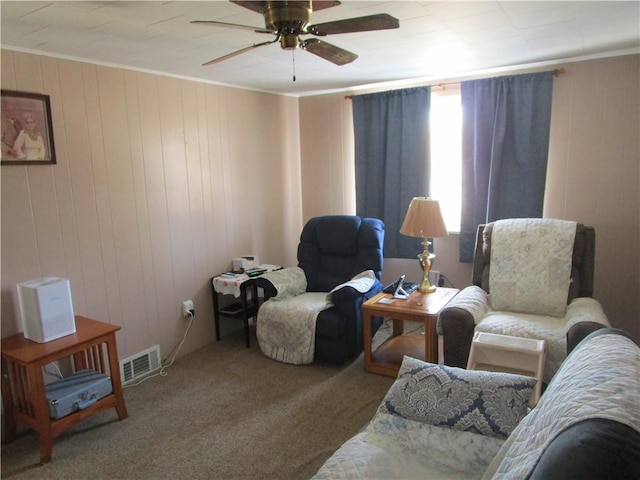 sitting room featuring crown molding, ceiling fan, carpet, and wood walls