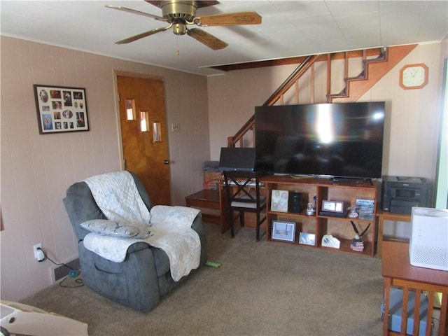 living room featuring carpet flooring, wooden walls, and ceiling fan