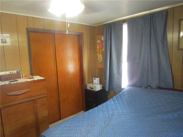 bedroom with crown molding, a closet, and wood walls