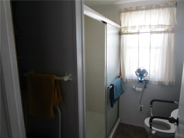 bathroom featuring toilet and a shower with shower door