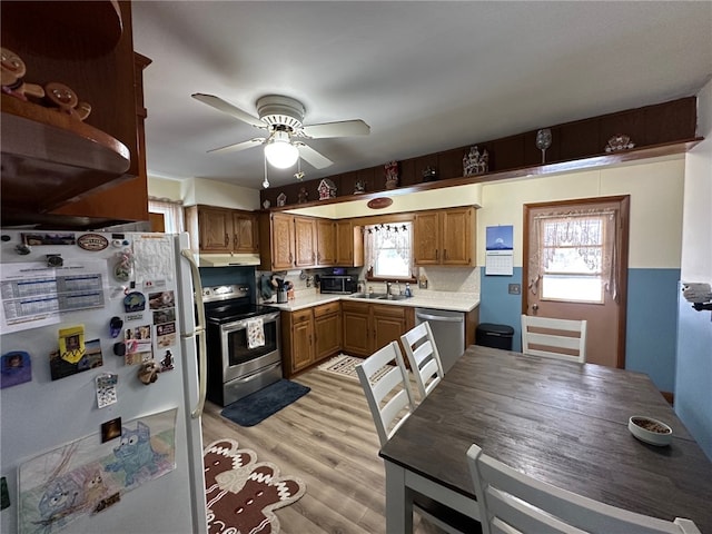 kitchen with ceiling fan, appliances with stainless steel finishes, sink, and light hardwood / wood-style floors