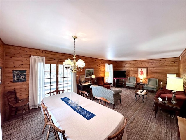 dining area with wood walls, carpet flooring, and a notable chandelier