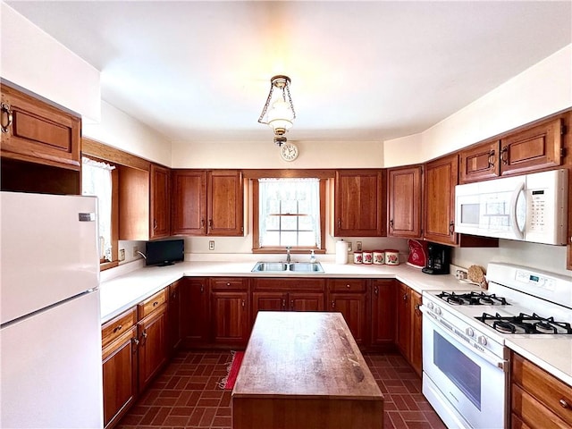 kitchen featuring pendant lighting, sink, white appliances, and a kitchen island