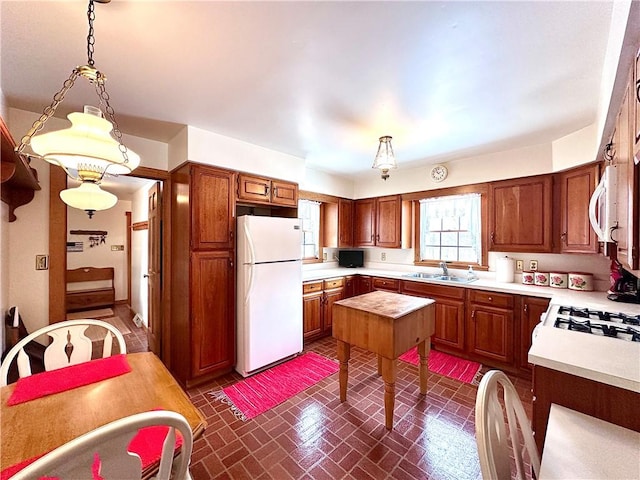 kitchen featuring sink, white appliances, and decorative light fixtures