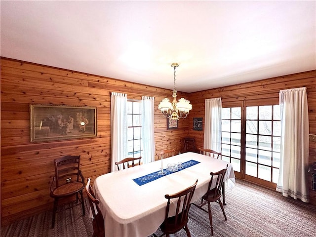 carpeted dining area with a chandelier and a wealth of natural light