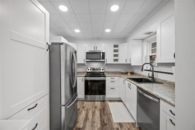 kitchen featuring appliances with stainless steel finishes, white cabinetry, sink, light stone counters, and dark wood-type flooring