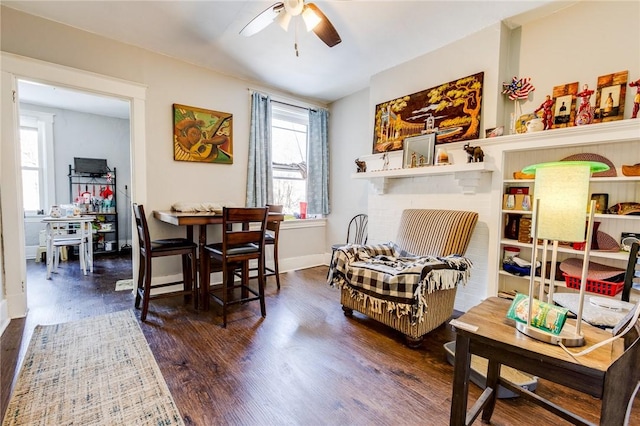 living area with dark wood-type flooring and ceiling fan