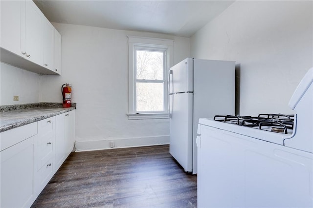 kitchen with light stone countertops, dark hardwood / wood-style floors, white cabinets, and white refrigerator