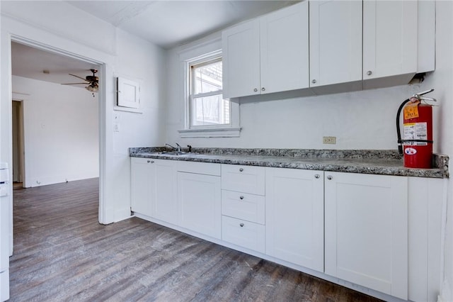 kitchen with dark wood-type flooring, ceiling fan, sink, and white cabinets