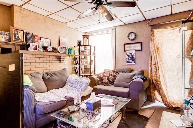 living room with carpet, a drop ceiling, and ceiling fan