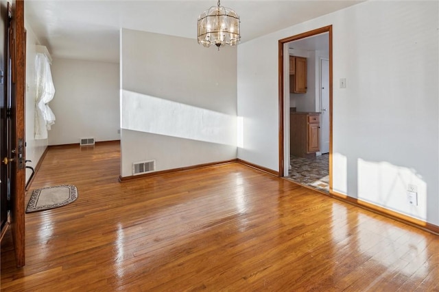 unfurnished room with a chandelier and hardwood / wood-style floors