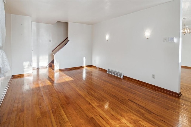 unfurnished room featuring wood-type flooring and a chandelier