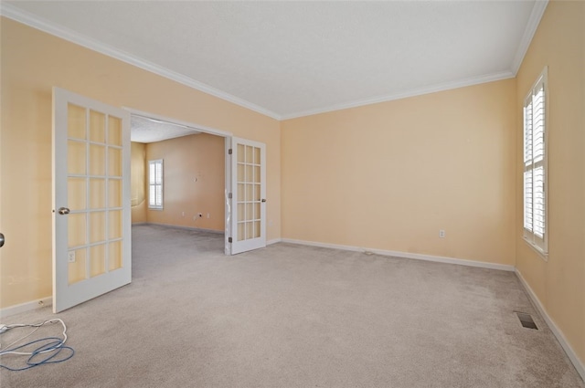 spare room featuring french doors, ornamental molding, and light carpet