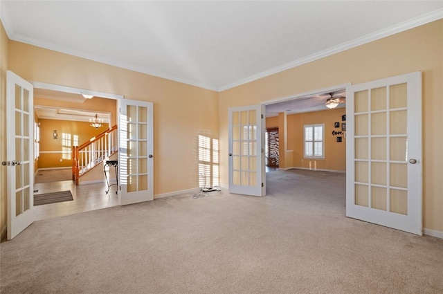 carpeted spare room featuring french doors, crown molding, and a chandelier