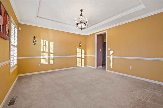 carpeted empty room featuring a raised ceiling, crown molding, and an inviting chandelier