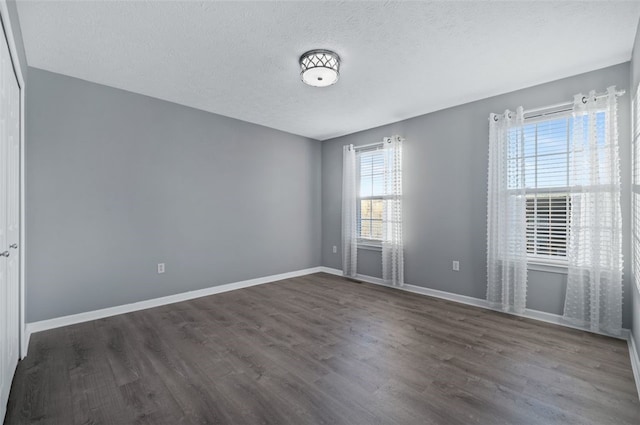 unfurnished room with dark wood-type flooring and a textured ceiling