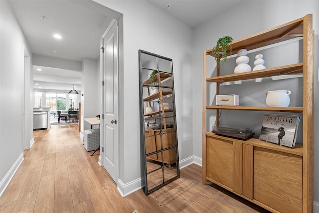 corridor with light wood-style floors, baseboards, and recessed lighting