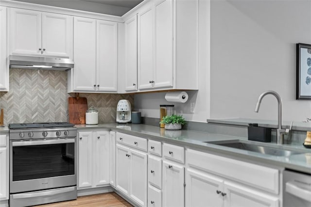 kitchen with gas stove, a sink, white cabinets, and under cabinet range hood