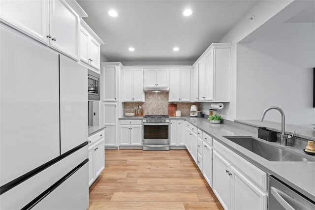 kitchen with white cabinets, stainless steel appliances, light wood-style floors, a sink, and recessed lighting