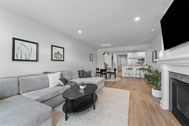 living room featuring a glass covered fireplace, light wood finished floors, and recessed lighting