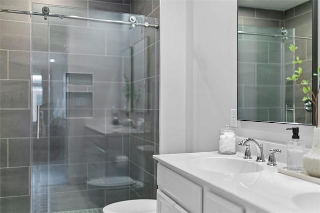 bathroom featuring double vanity, a shower stall, toilet, and a sink