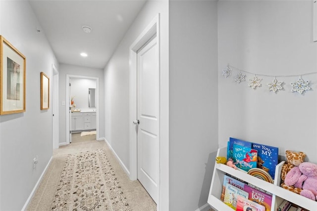 hall with baseboards and light colored carpet